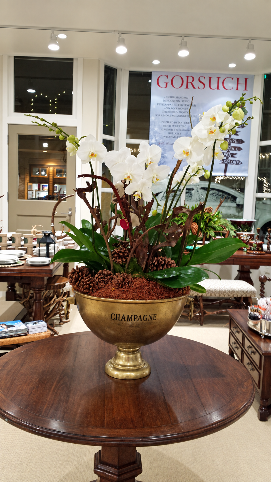 Large white orchid arrangement in a brass champagne vessel created for the Gorsuch grand opening.
