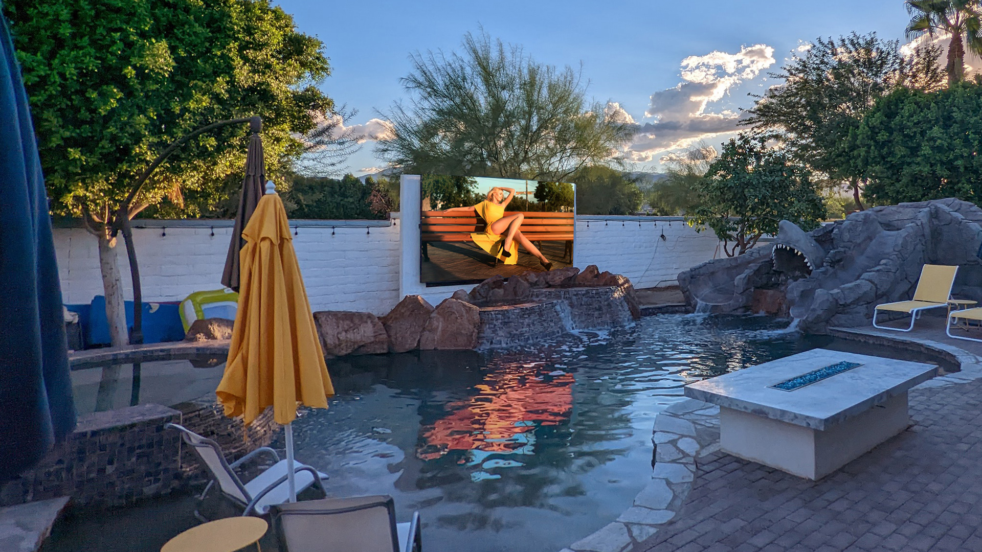 Desert backyard entertainment setup with a YOLO outdoor screen anchoring a short-term rental property