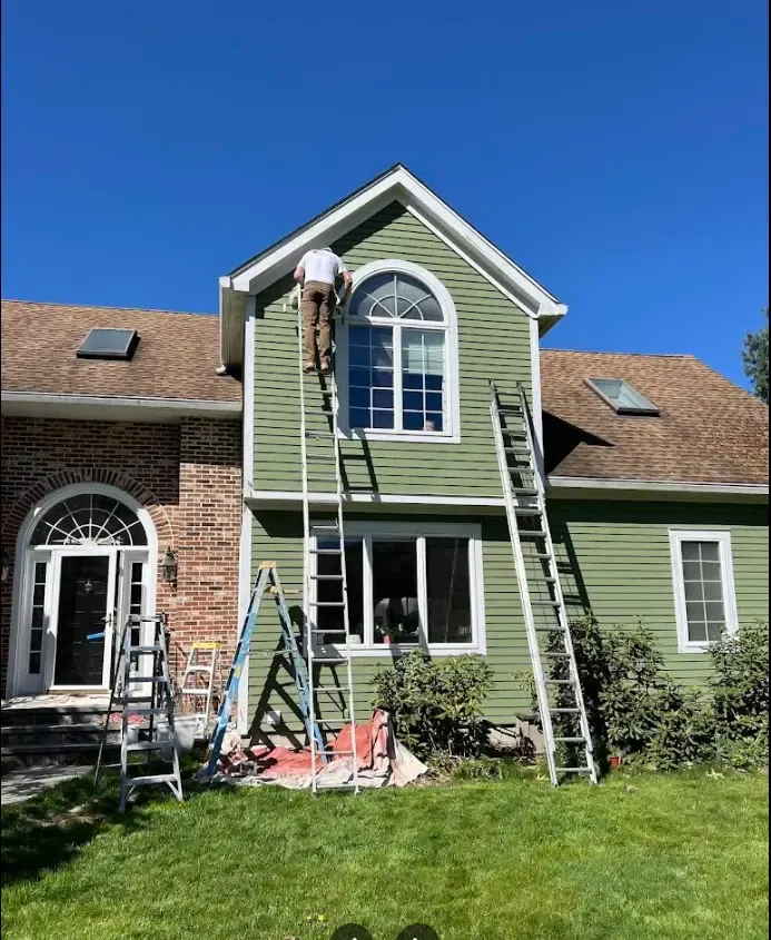 Green two-story home exterior, ladders up