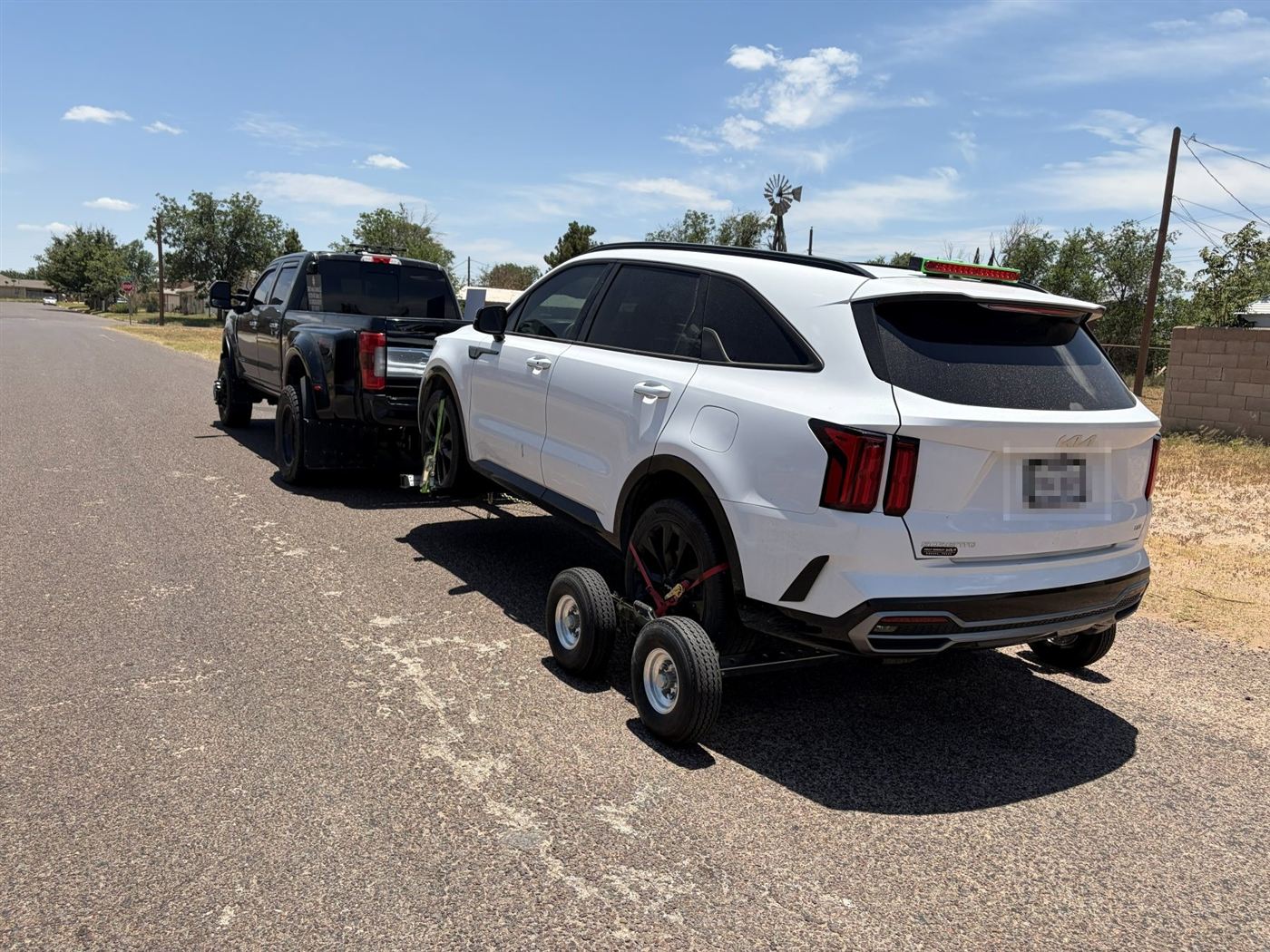 White Kia SUV on tow dollies