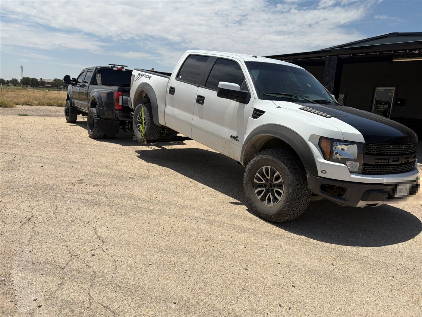 White Ford Raptor on a wheel-lift tow
