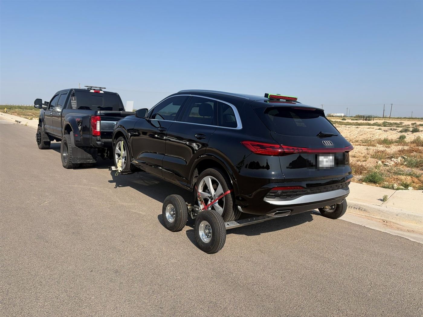 Black Audi SUV on tow dollies