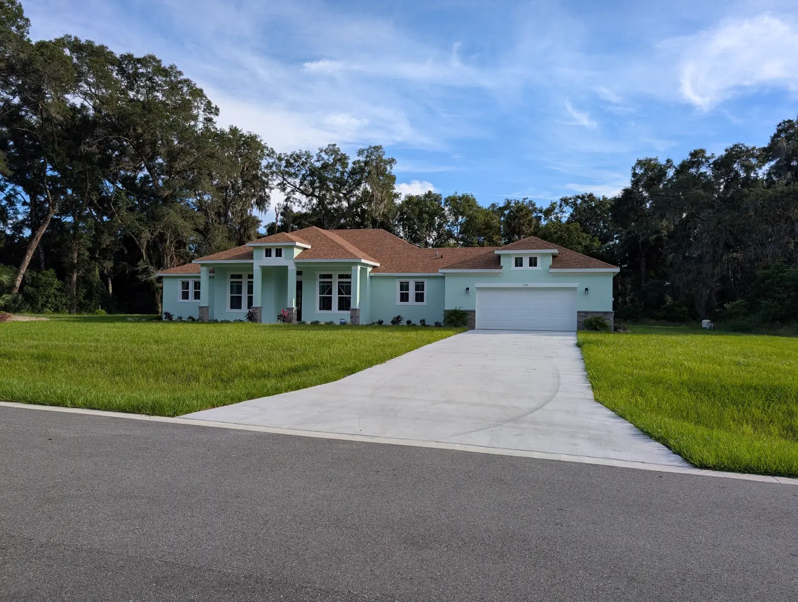 A finished one-story home in Heebner Acres, DeLand FL, on a wide lawn with old oak trees behind it