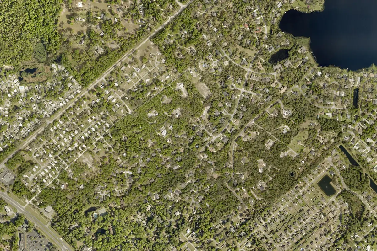 2024 Volusia County aerial photo of the Trails West neighborhood in north DeLand, FL, with tree-covered streets and a lake
