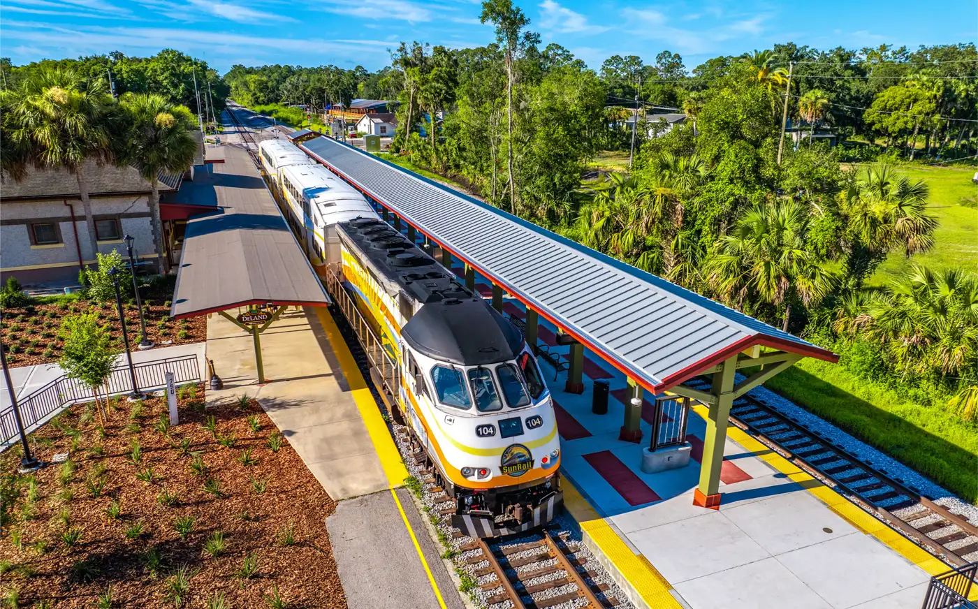 A SunRail train at the DeLand station platform, beside the old brick depot, seen from above