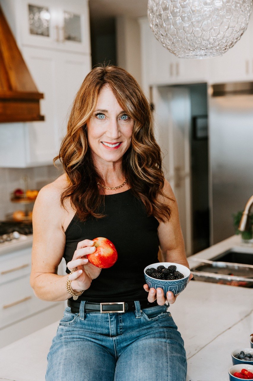 Dana Cushing, RN, holding a fork and spoon in her kitchen