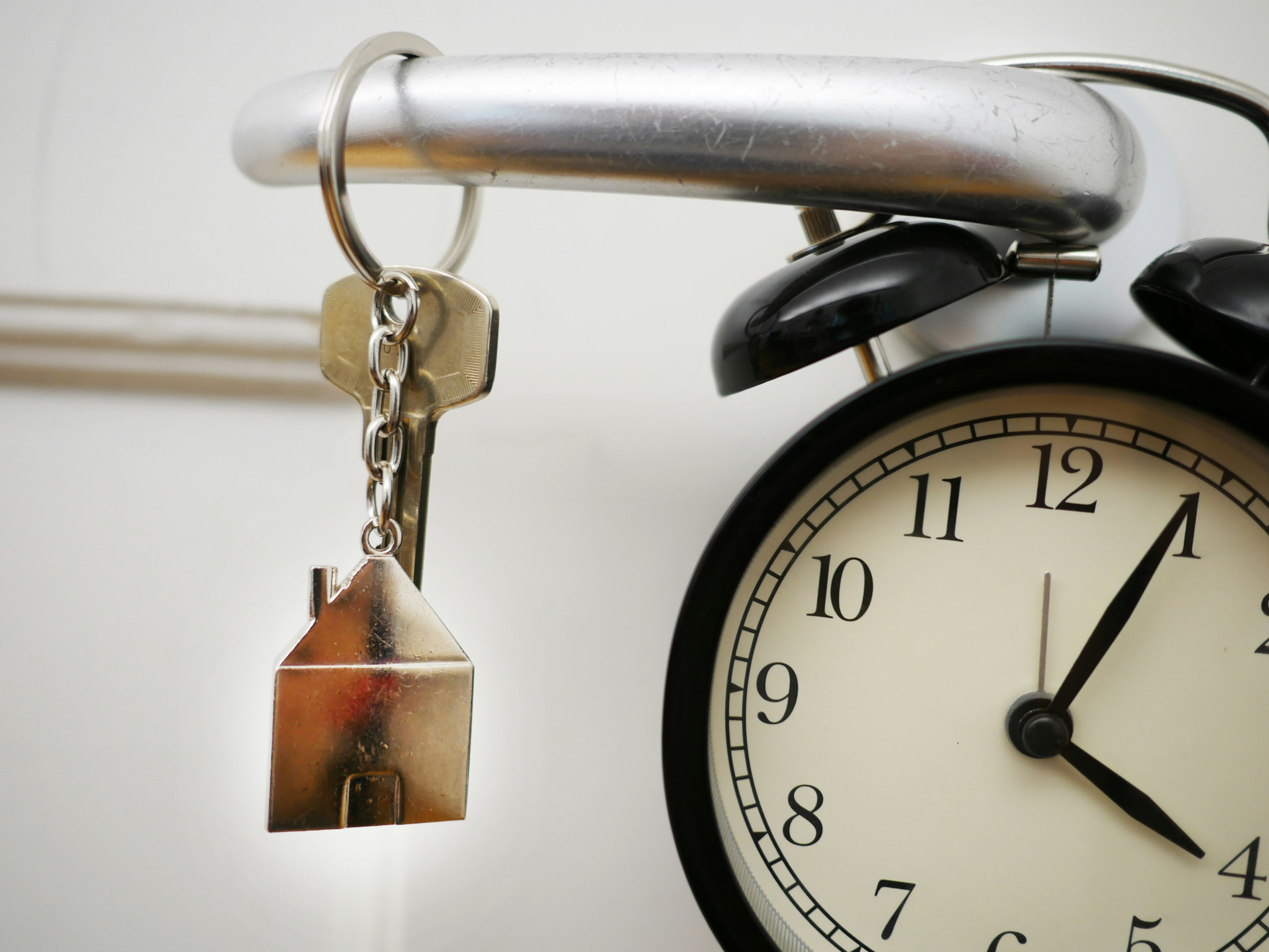 House keys hanging from a door handle next to a clock, symbolizing the importance of timing when buying or selling a home in Houston, Texas.