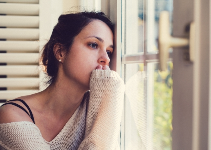 Depressed Woman Looking Out the Window with Gut Imbalances Affecting Brain Chemistry