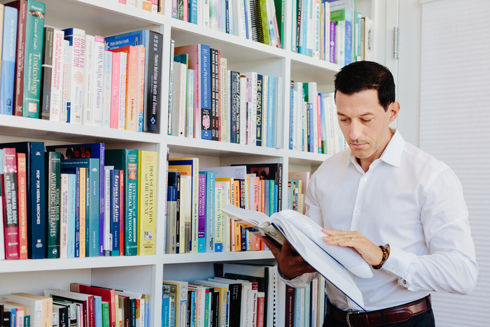 Dr. Stephen Cabral Reading Books from Bookshelf