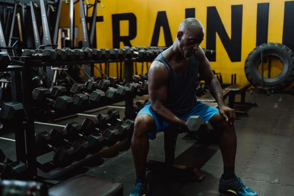 Middle-aged man resting between sets of dumbbell curls at the gym