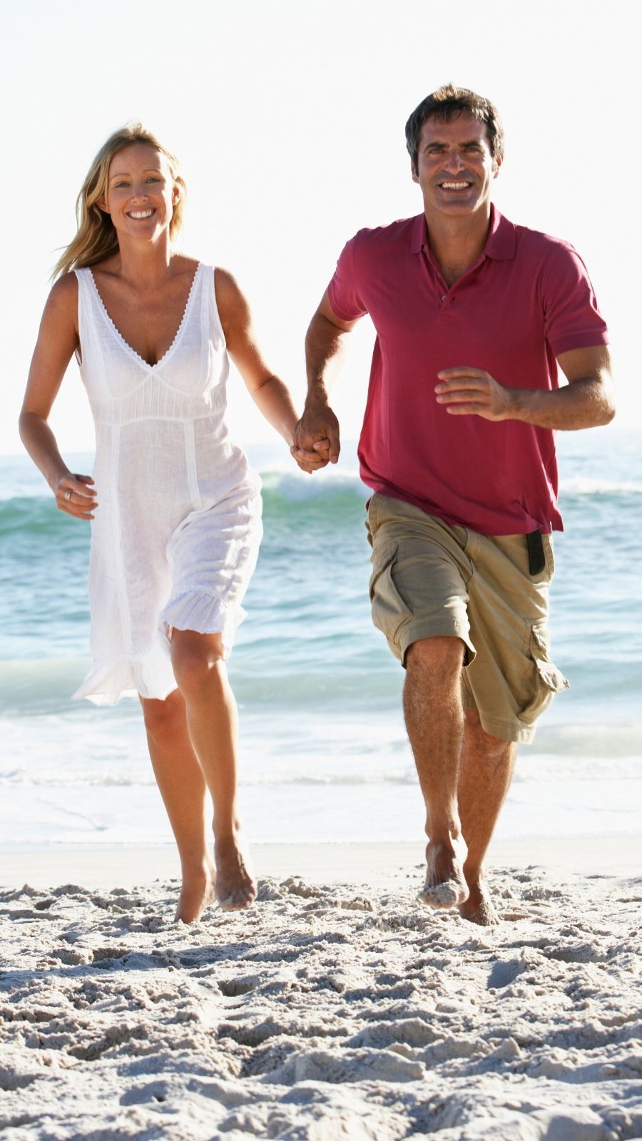 Smiling couple running hand in hand along a beach