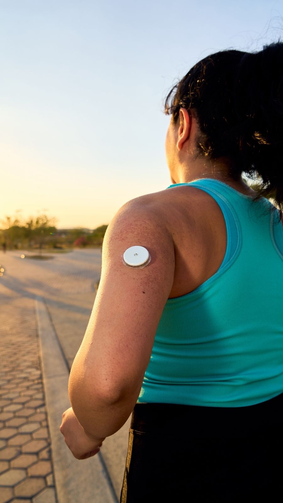 Woman on an evening walk wearing a continuous glucose monitor on the back of her arm