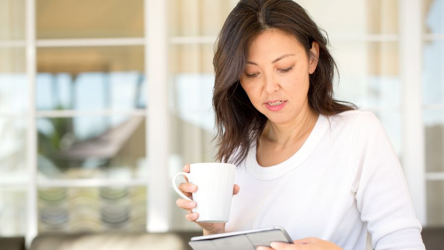 A woman with a cup of tea and a journal.