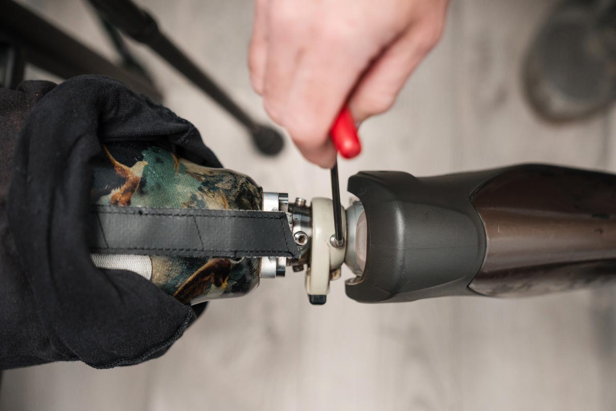 Close-up of a prosthetic leg being adjusted with a hand tool during a follow-up fitting.