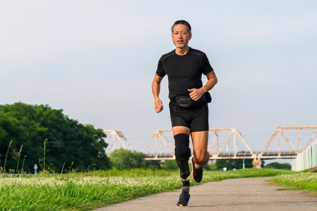 Adult runner using a prosthetic leg on an outdoor path, showing confidence and mobility.