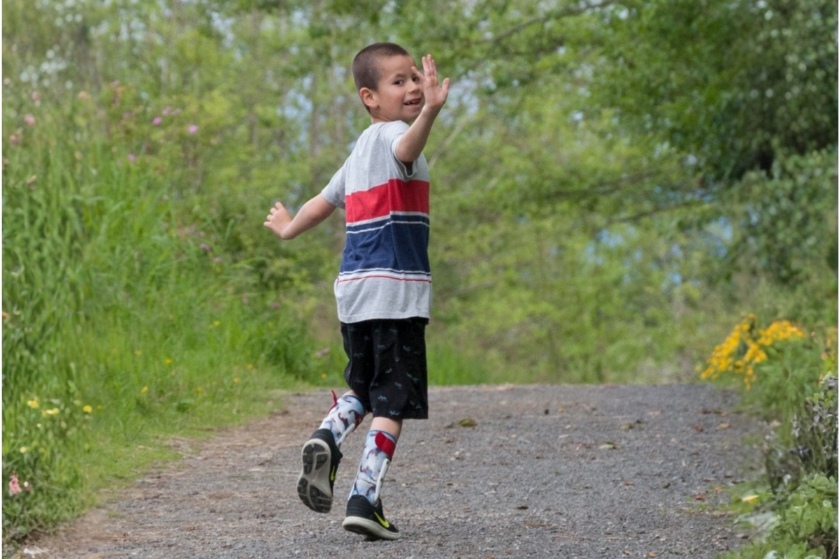 Child actively moving while wearing orthotic devices, demonstrating increased stability and mobility support.