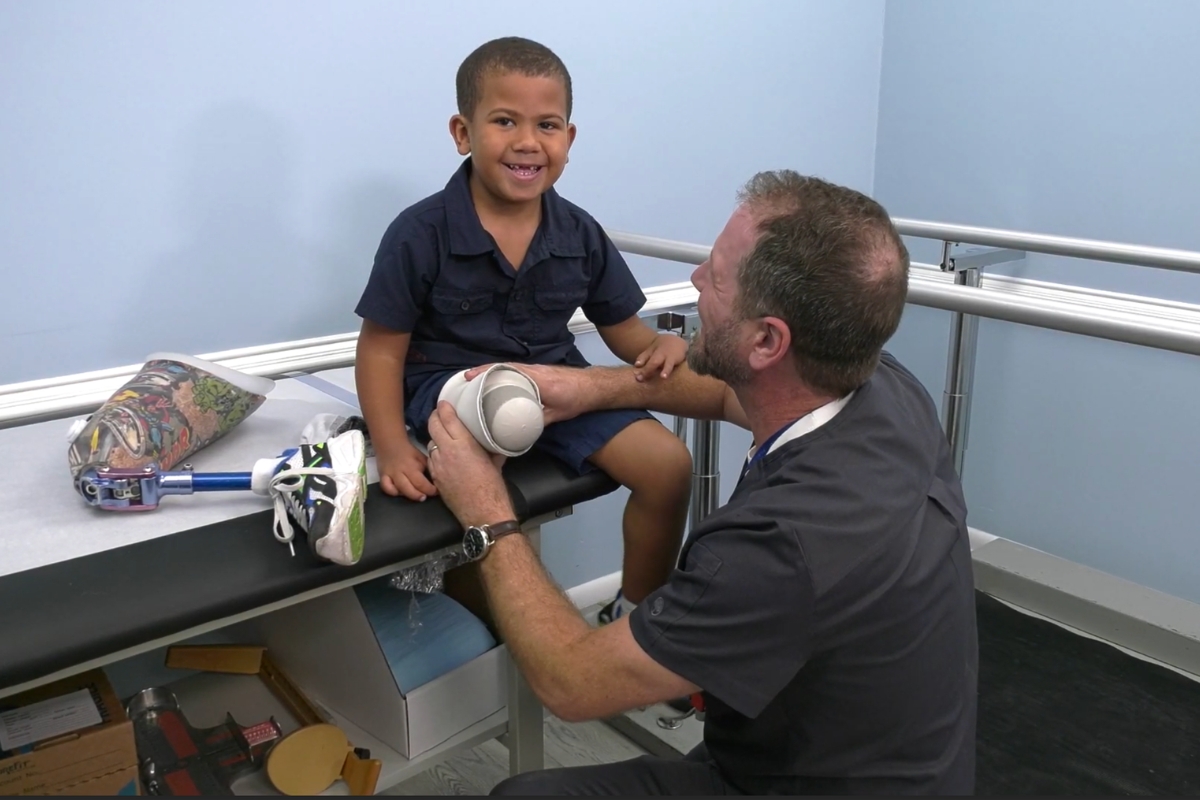 Clinician adjusting a prosthetic leg for a child patient, ensuring correct fit and comfort during movement.