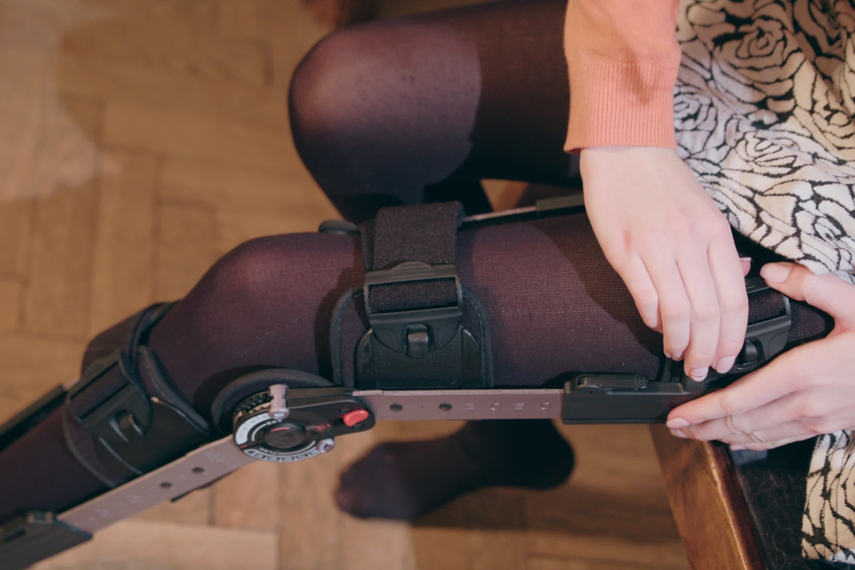 Patient practicing how to put on and adjust a custom leg orthosis during a fitting appointment