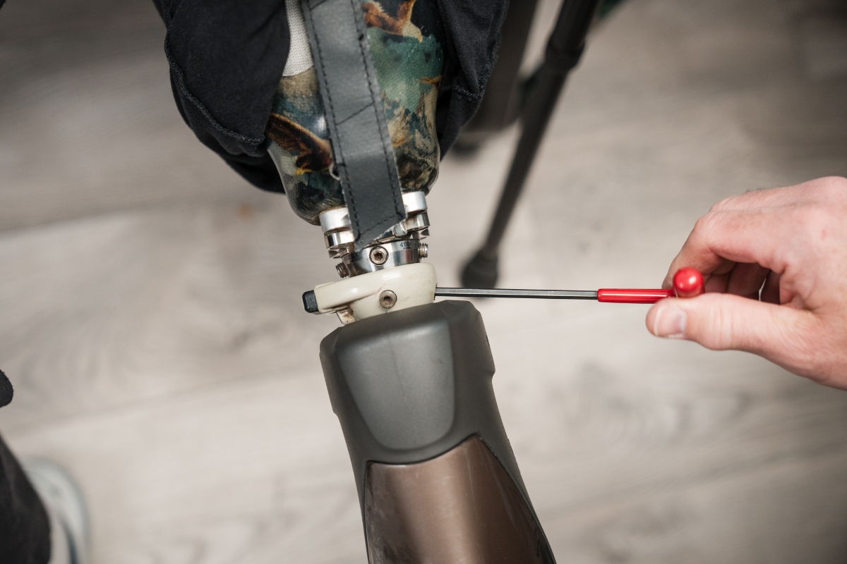 Prosthetist tightening a lower-limb prosthesis during a follow-up adjustment appointment