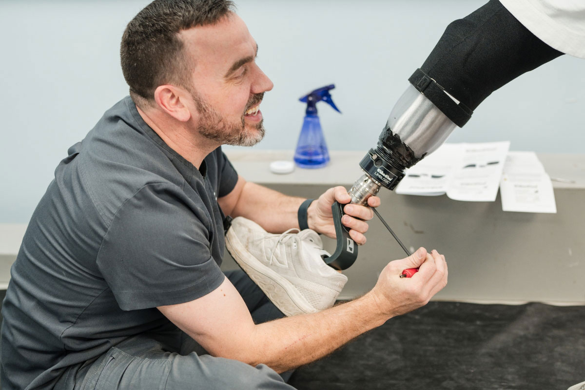 Prosthetist adjusting a lower-limb prosthesis during a follow-up visit for comfort and stability