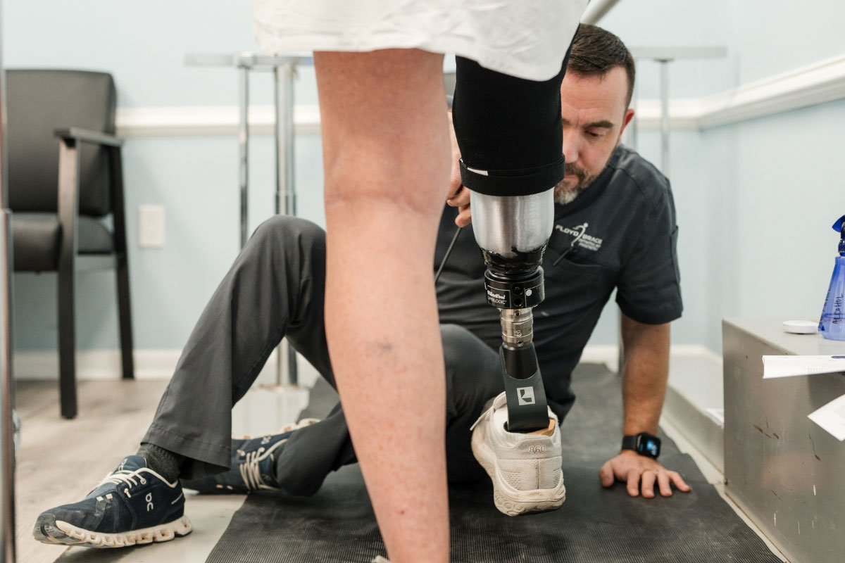 Prosthetist checking a patient’s lower-limb prosthesis during a gait and alignment follow-up