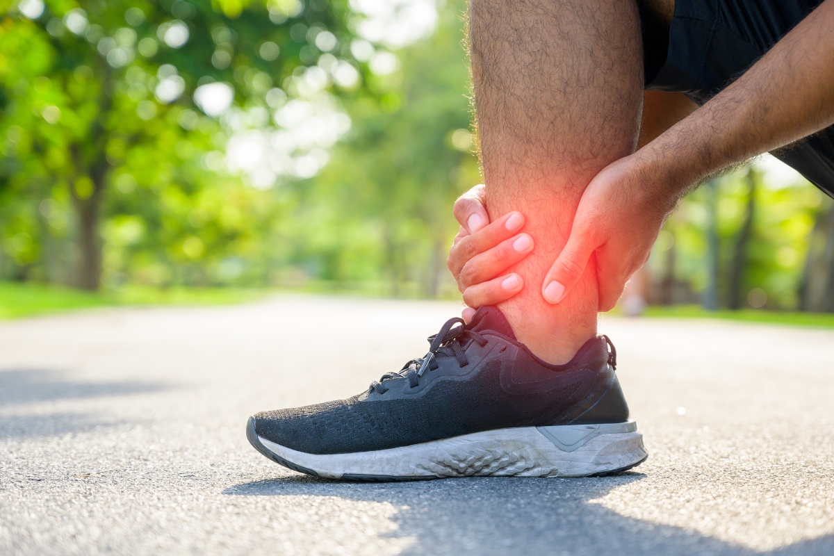 Close-up of a person holding an unstable, painful ankle joint while wearing a walking sneaker Close-up of a person holding an unstable, painful ankle joint while wearing a walking sneaker
