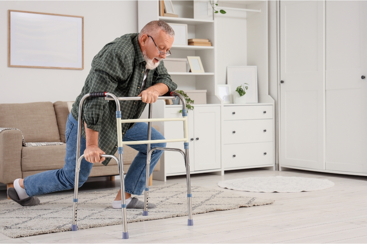 Senior man relying on a mobility walker at home to maintain balance while getting up from a fall Senior man relying on a mobility walker at home to maintain balance while getting up from a fall