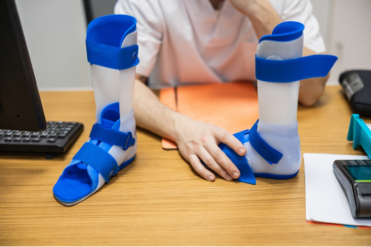 Pair of custom white and blue ankle-foot orthosis (AFO) braces resting on an orthotist's examination desk Pair of custom white and blue ankle-foot orthosis (AFO) braces resting on an orthotist's examination desk