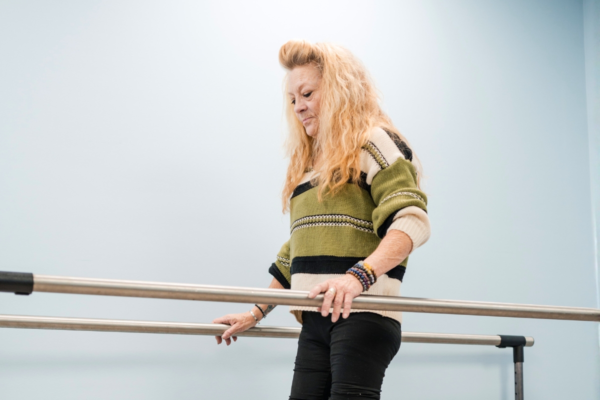 woman holding parallel bars during a clinical balance and gait analysis evaluation woman holding parallel bars during a clinical balance and gait analysis evaluation