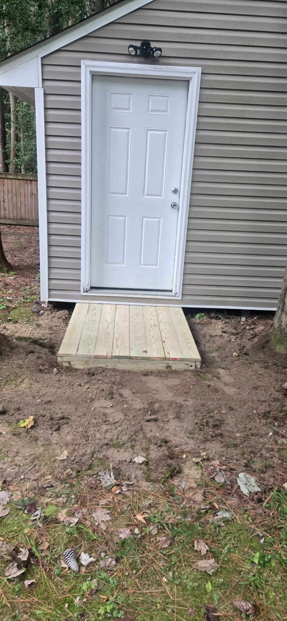 Finished pressure-treated shed step with decking boards laid flush to the door
