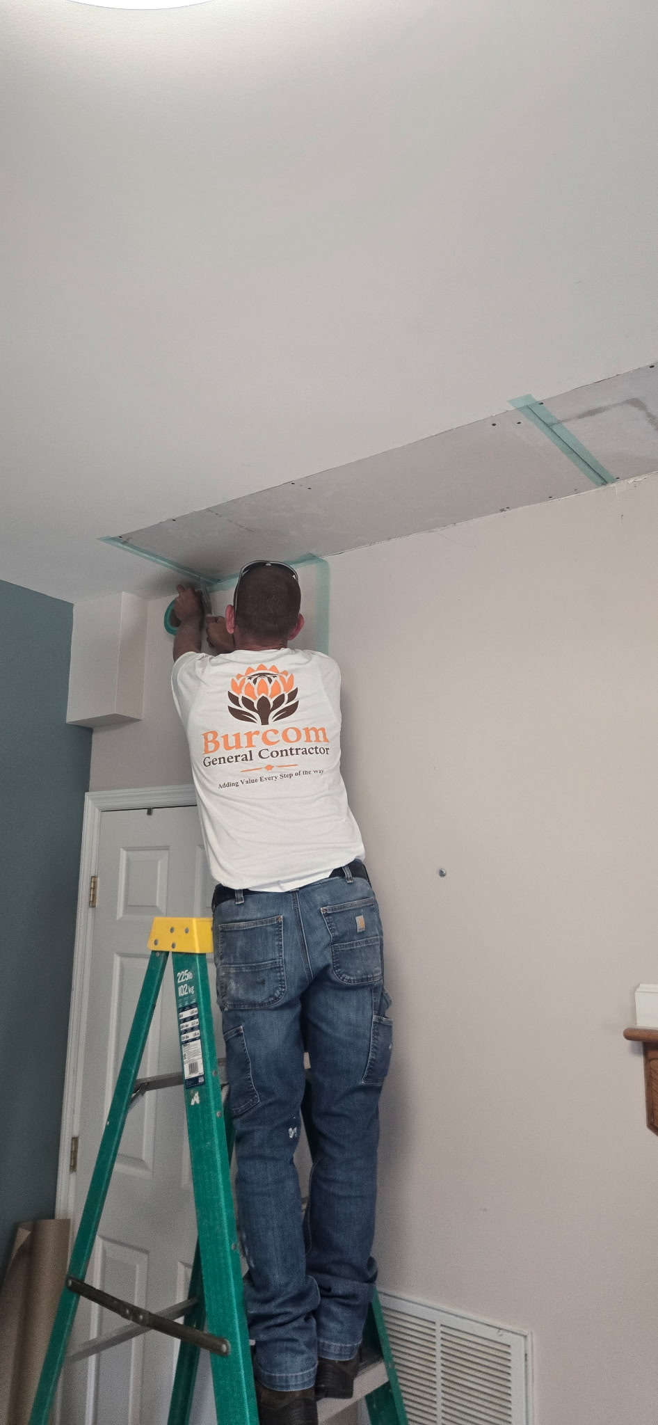 Francois on a ladder taping the joints of the new ceiling drywall by hand