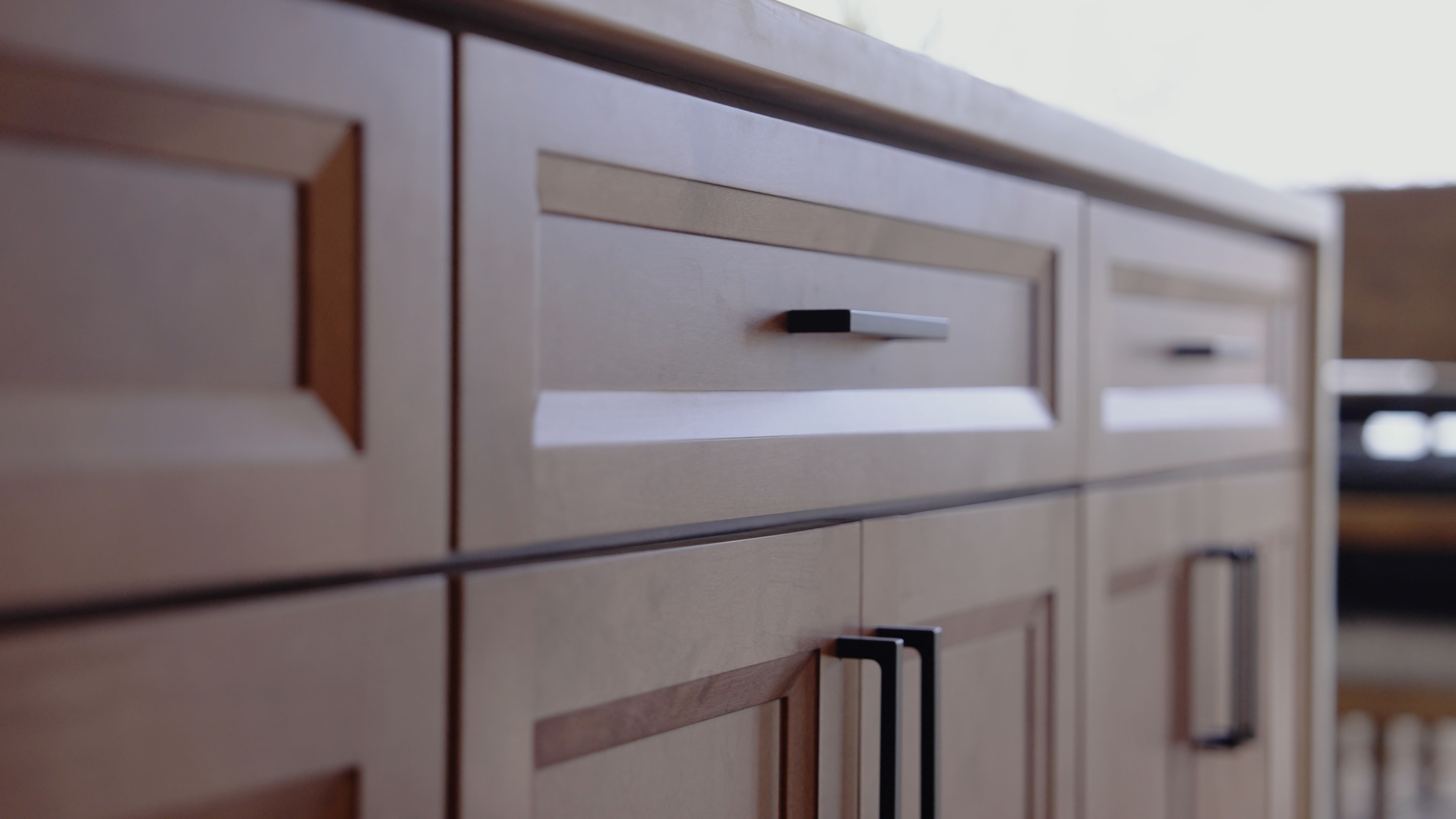 Close-up of custom shaker cabinet doors and drawer fronts in stained maple with matte black bar pulls