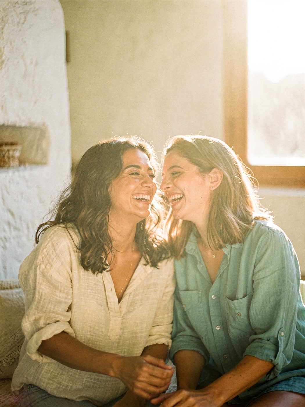 Dos mujeres riendo juntas con luz cálida