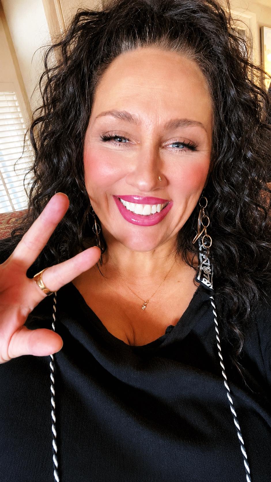 Confident woman wearing makeup, jewelry, and styled hair standing proudly as a symbol of self-expression, female empowerment, and body autonomy.