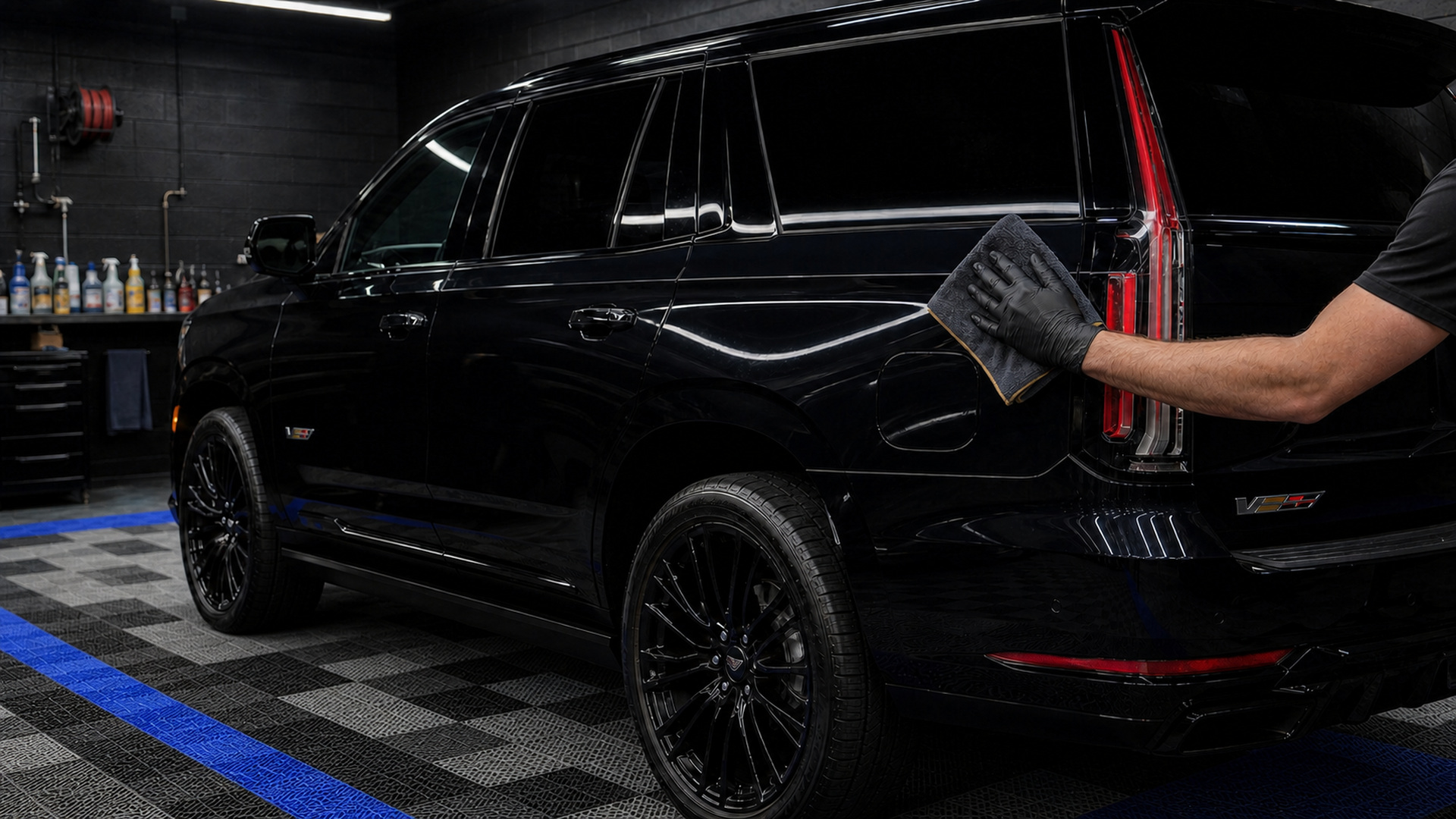 Black Cadillac Escalade-V beneath three detailing inspection-light bays