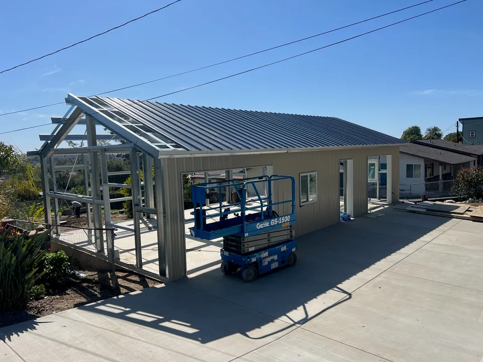 Residential metal workshop with roofing and wall panels being installed.