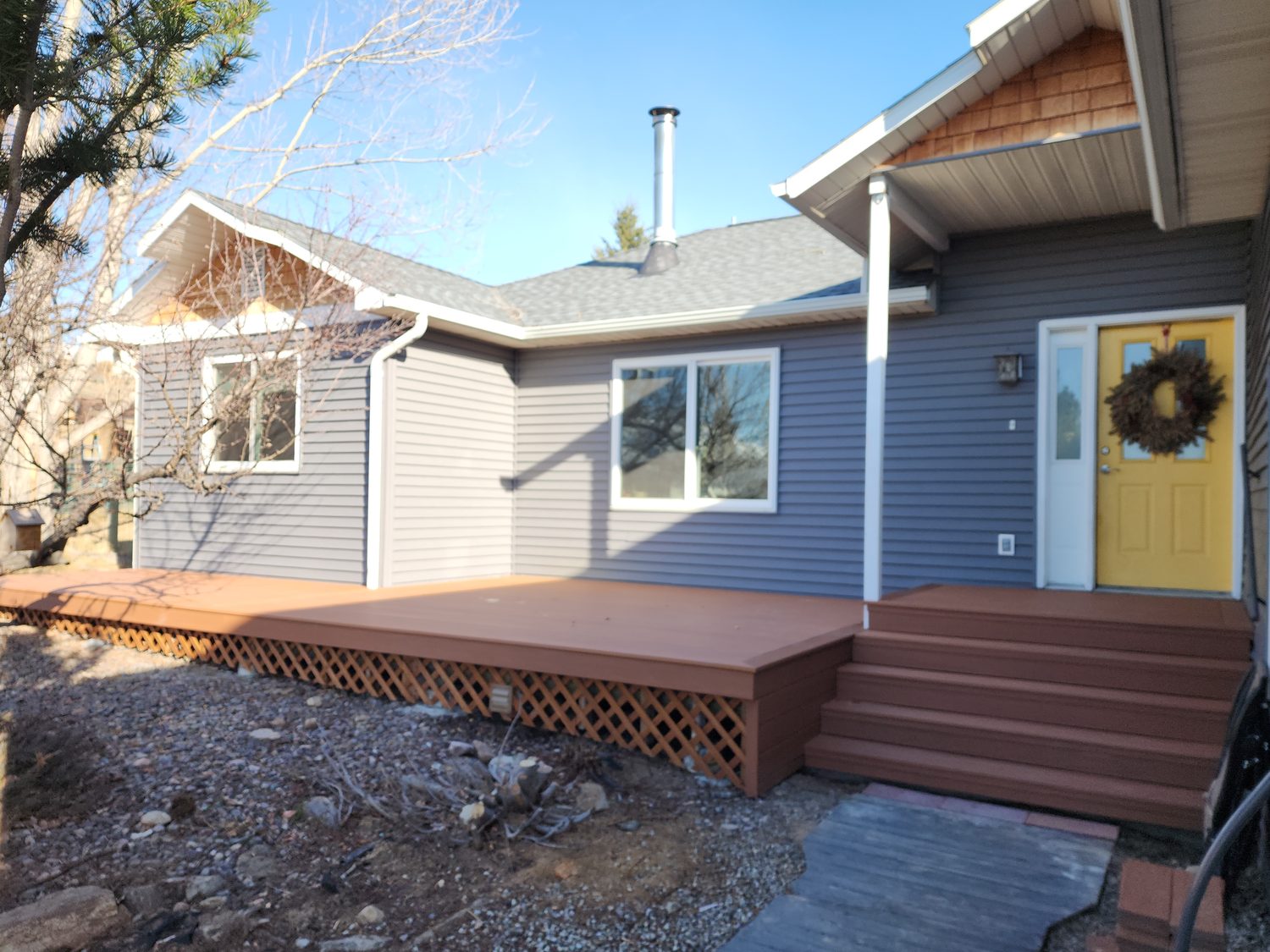 Low wraparound wood deck with lattice skirting along the front of a home