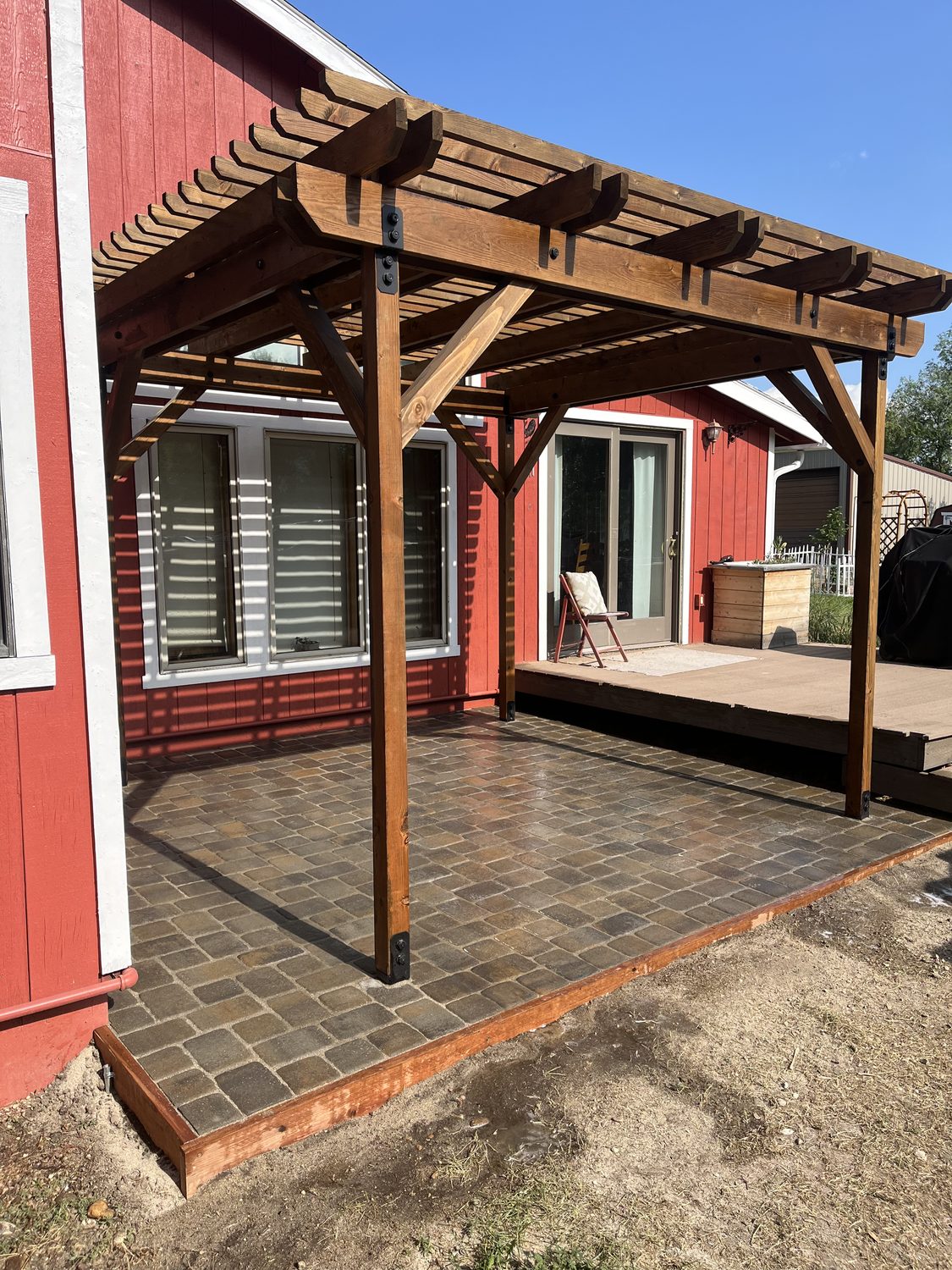 Large stained-wood pergola over a paver patio beside a home