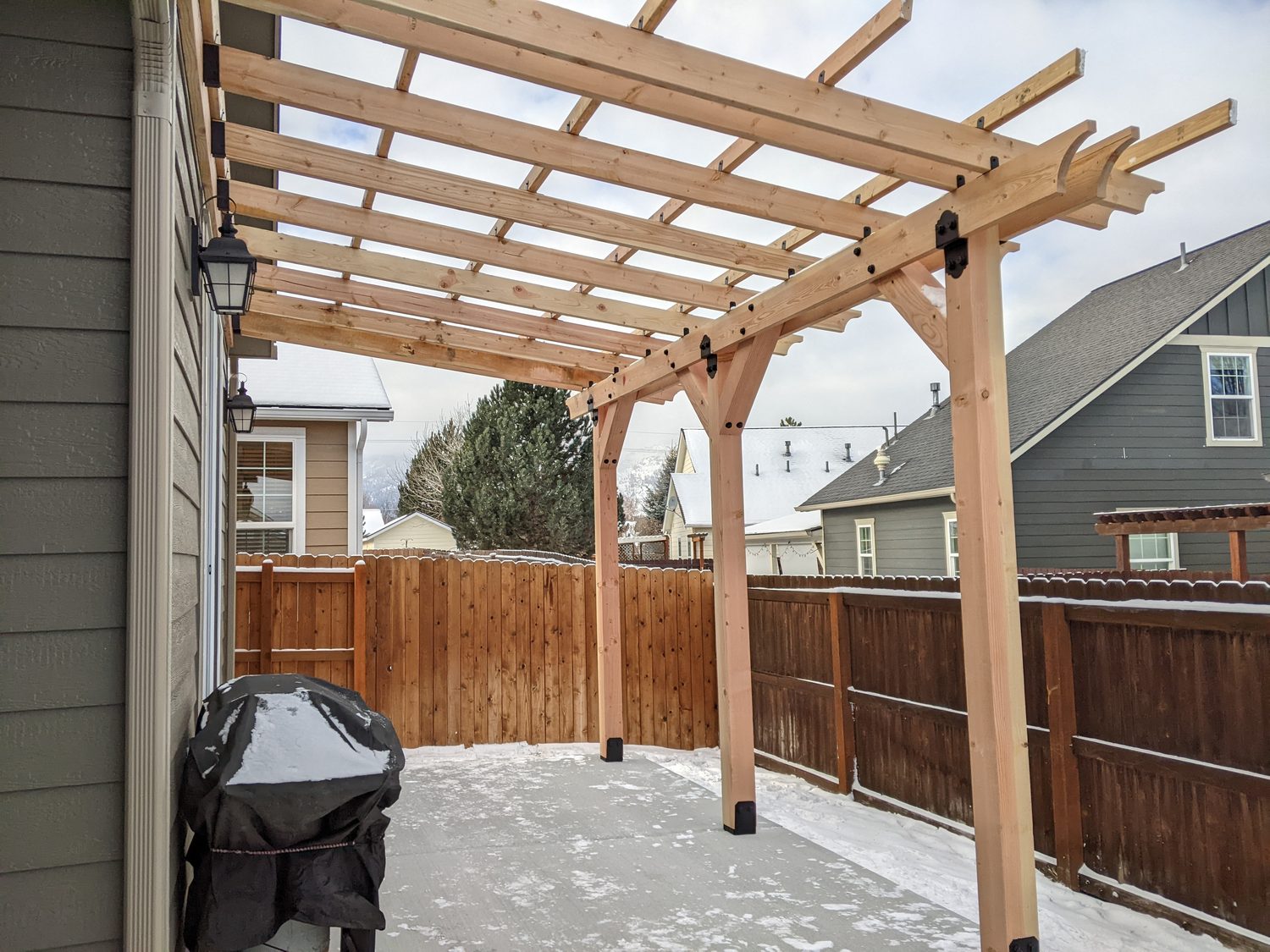 Newly built cedar pergola over a patio with mountains behind