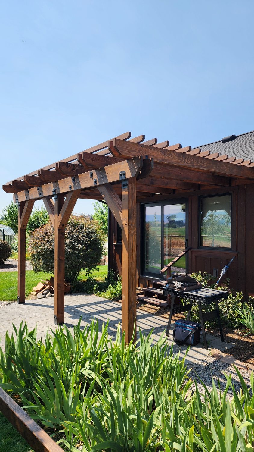 Custom stained-wood pergola over a paver patio attached to a home