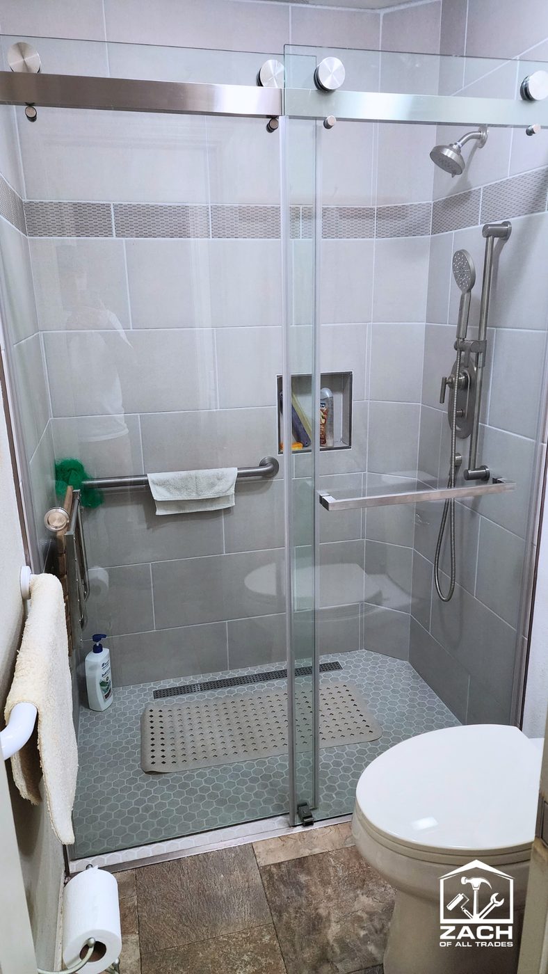 Gray large-format tile shower with sliding glass door and niche