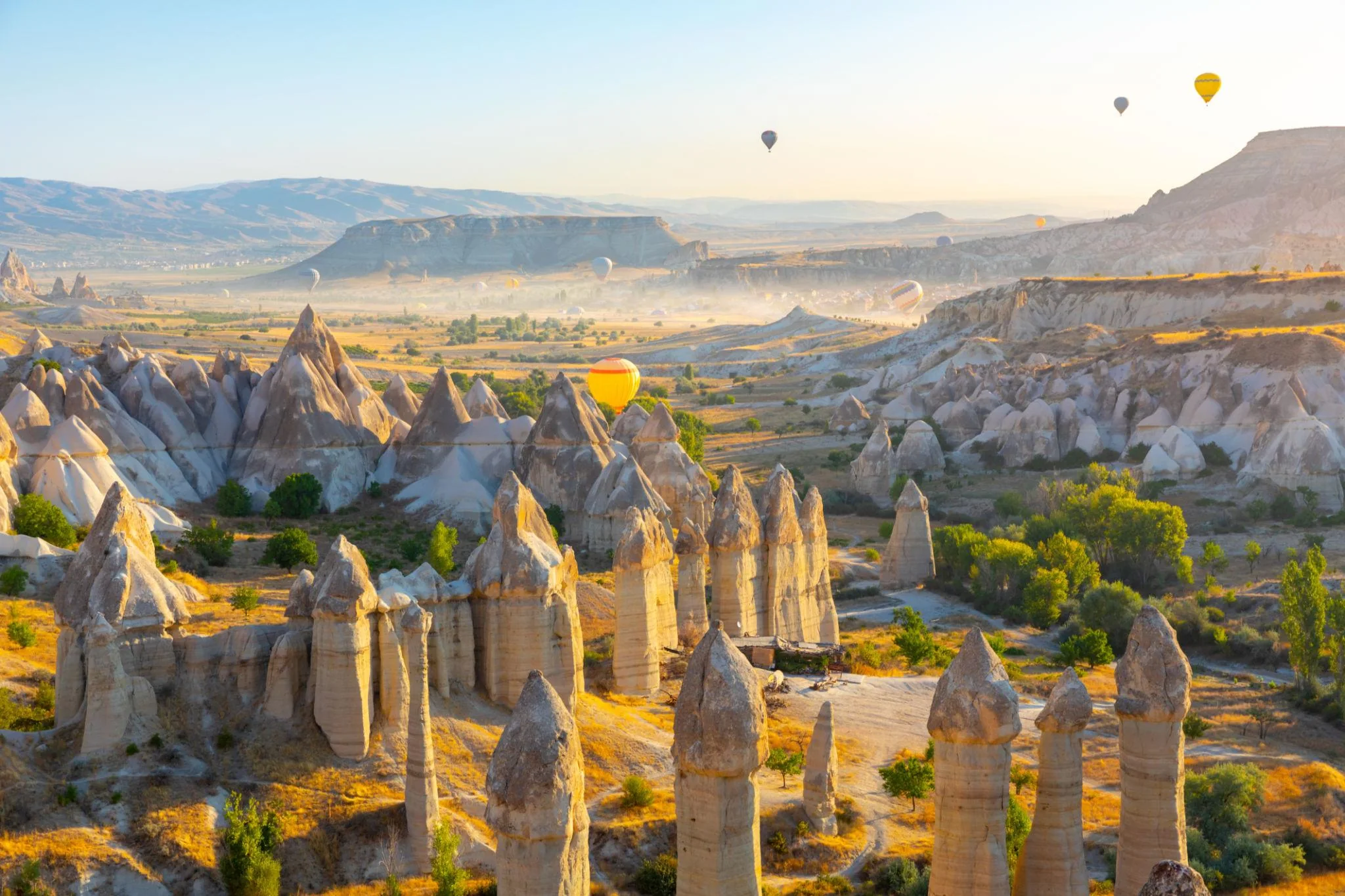 Hot air balloons floating above Cappadocia at sunrise