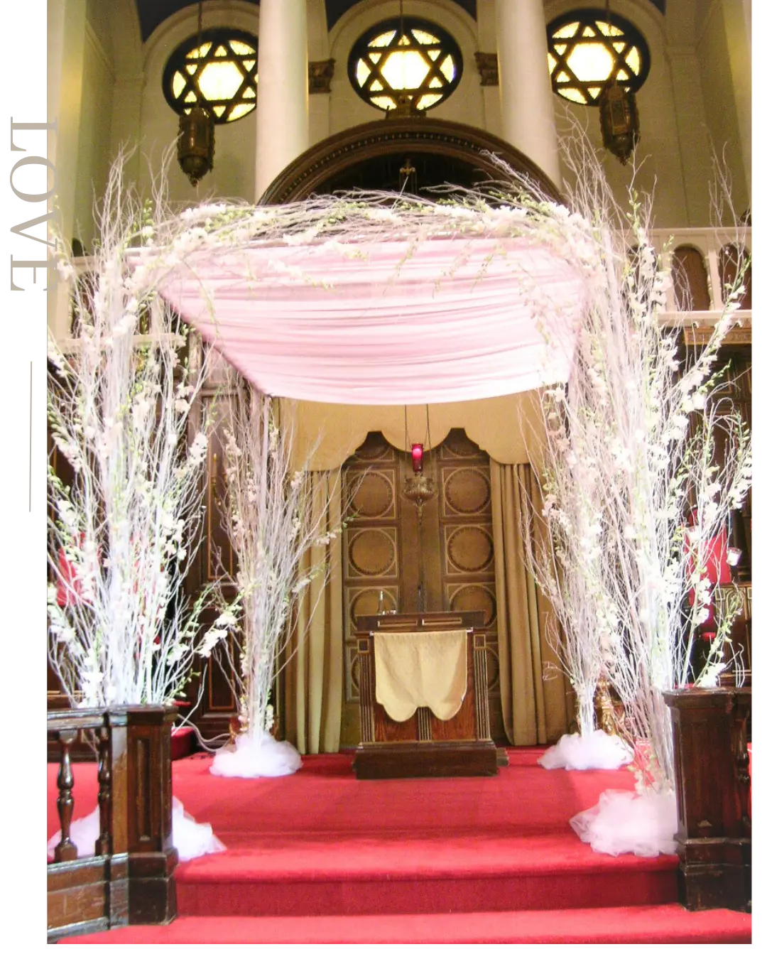 Elegant synagogue chuppah with soft blush draping and white branch floral décor for a Jewish wedding ceremony
