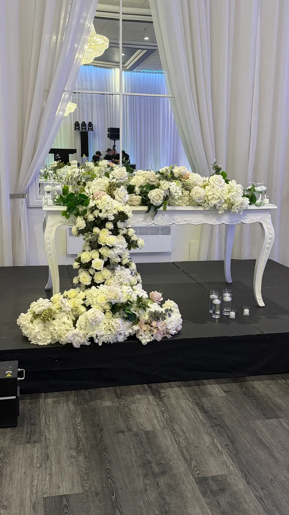 Artificial white roses and hydrangeas cascading from a wedding head table