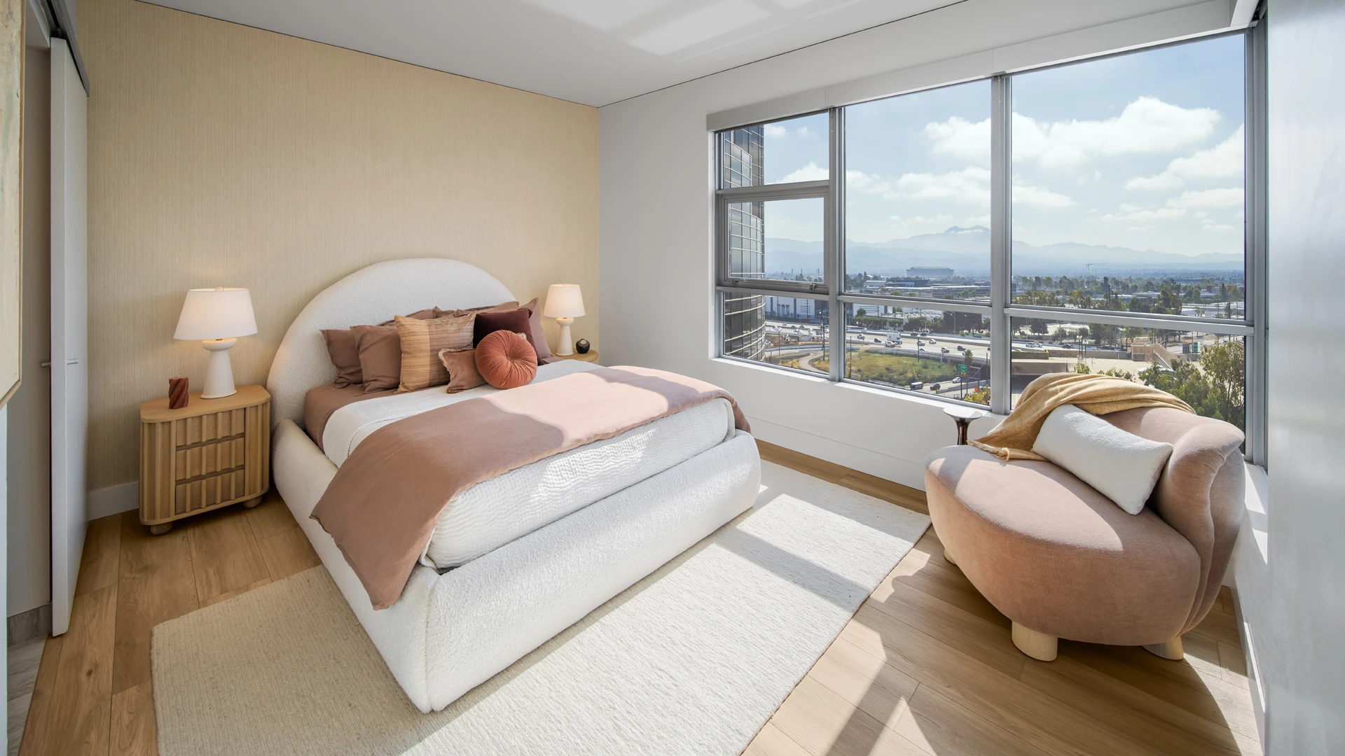 Primary bedroom at Skyline OC with panoramic city and mountain views through floor-to-ceiling windows