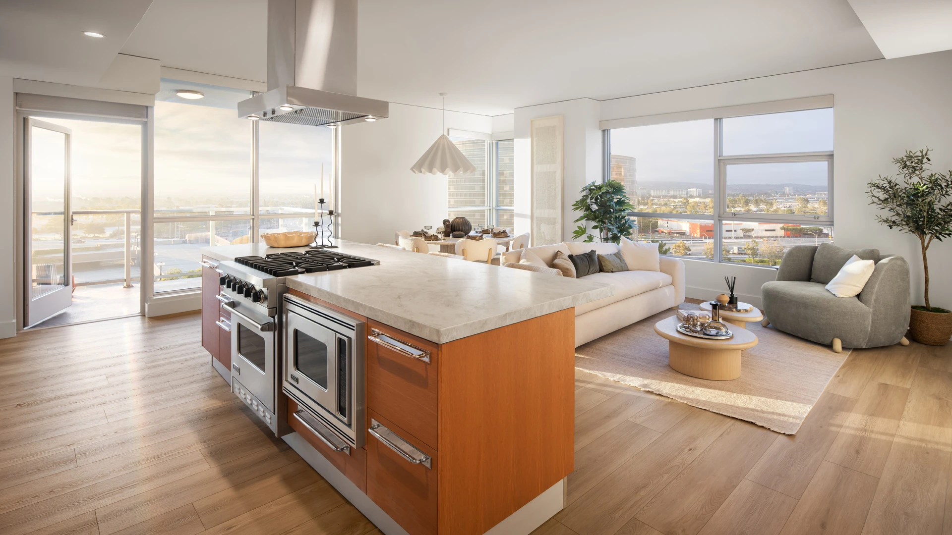Skyline OC kitchen with large waterfall island, integrated appliances, wood cabinetry, and balcony with mountain views