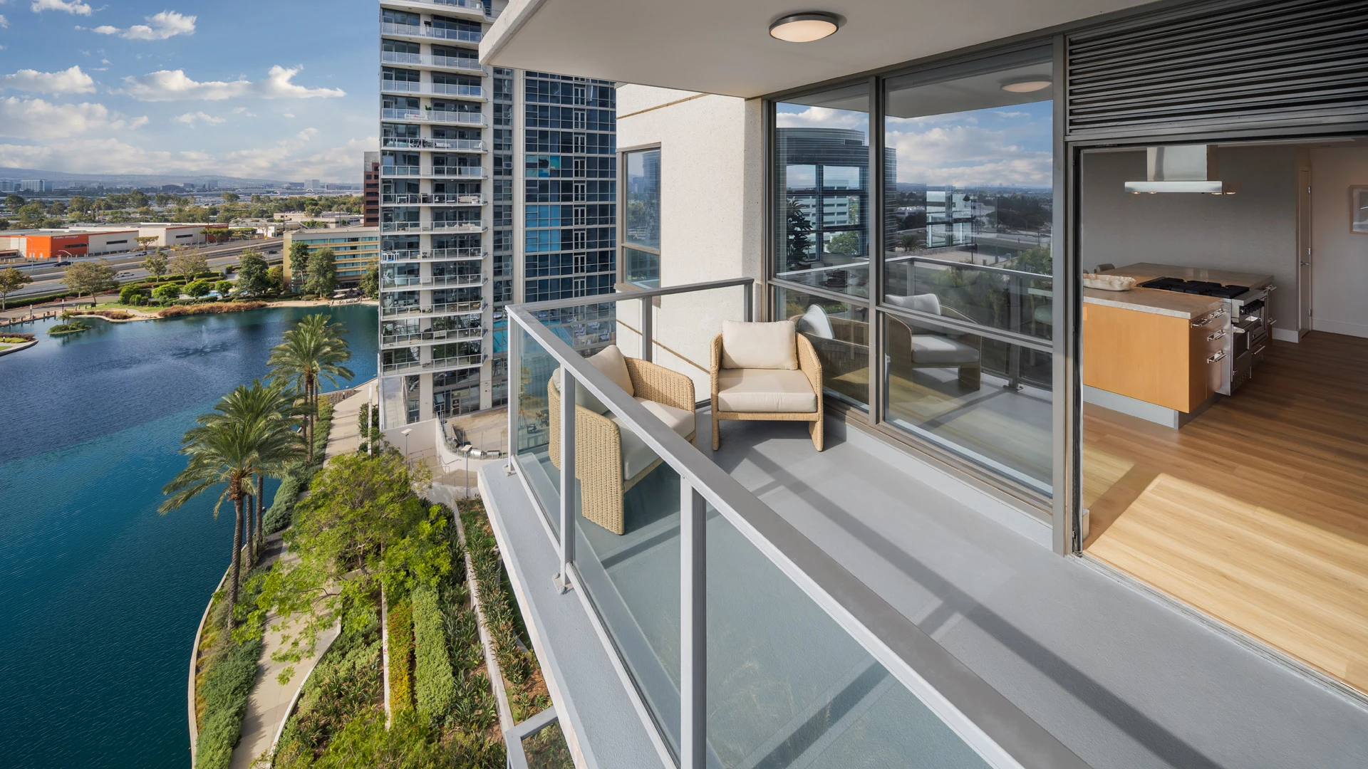 Private balcony terrace at Skyline OC South Coast with woven lounge chairs and panoramic waterfront and city views