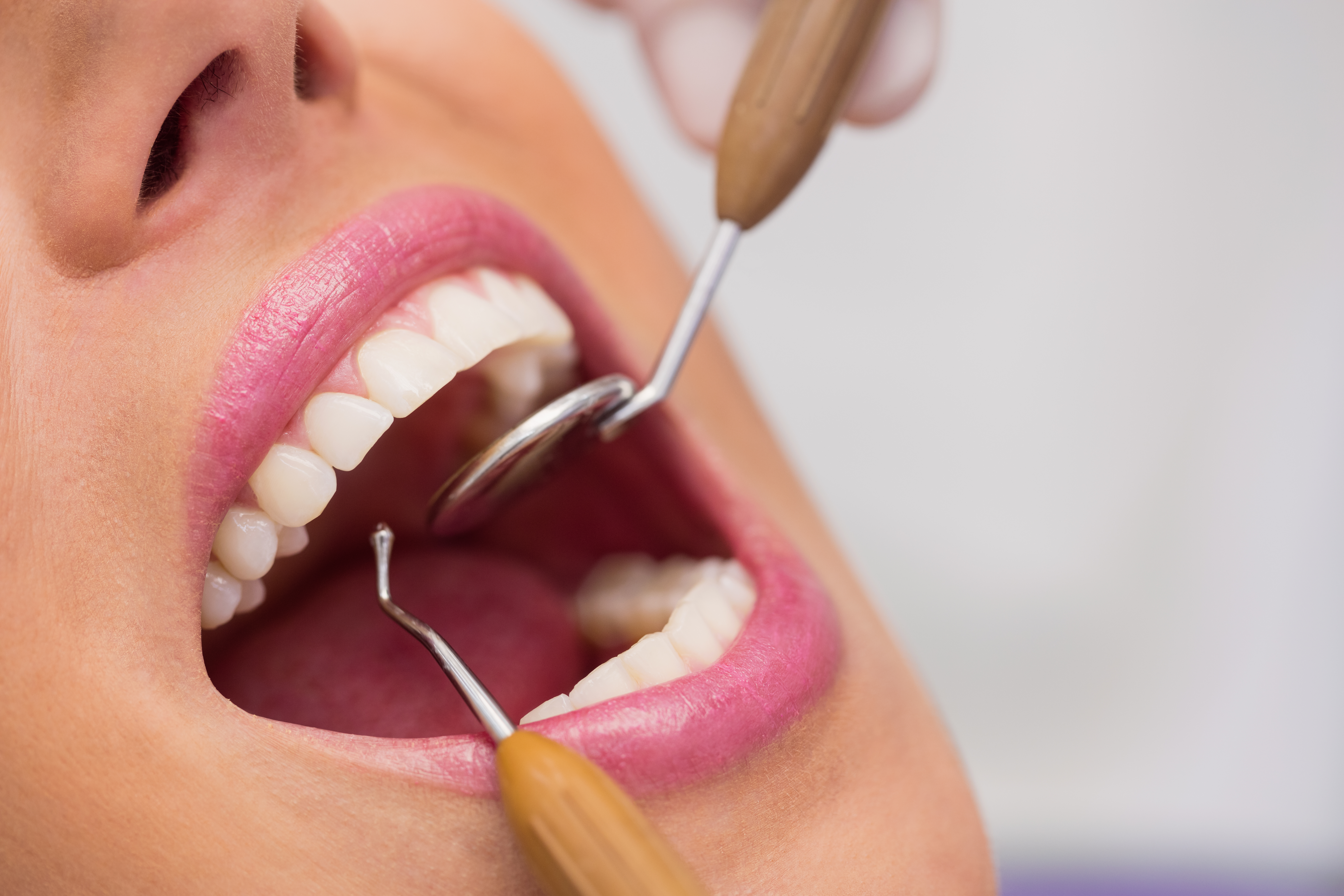 A dentist examining a patient's teeth with a mirror and probe