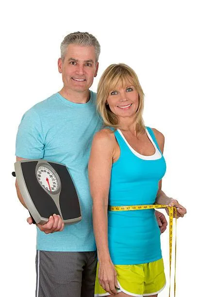 Couple celebrating weight loss with a scale and measuring tape