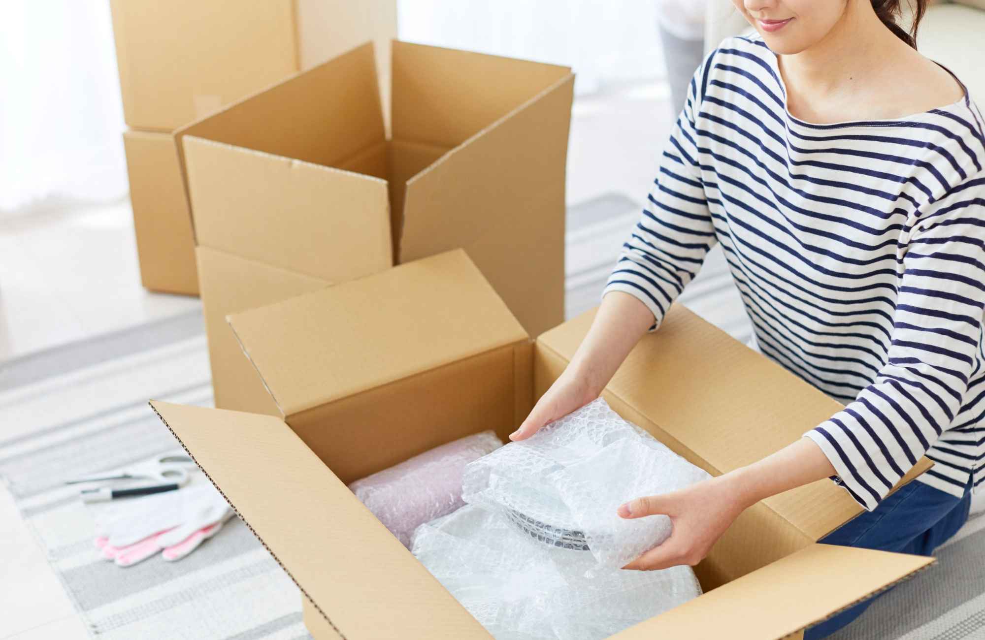 professional-home-organizing-service-castle-pines-co-letting-go-of-sentimental-items-woman-packing-china-plates-with-bubble-wrap-in-box-time-saving